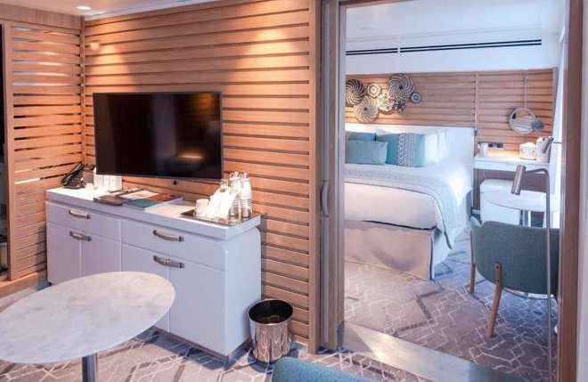 Interior suite Le Jacques Cartier dengan tempat tidur besar dan jendela geser menghadap laut