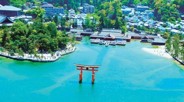 Itsukushima Shrine dan gerbang torii vermilion di atas air hijau kebiruan di Miyajima